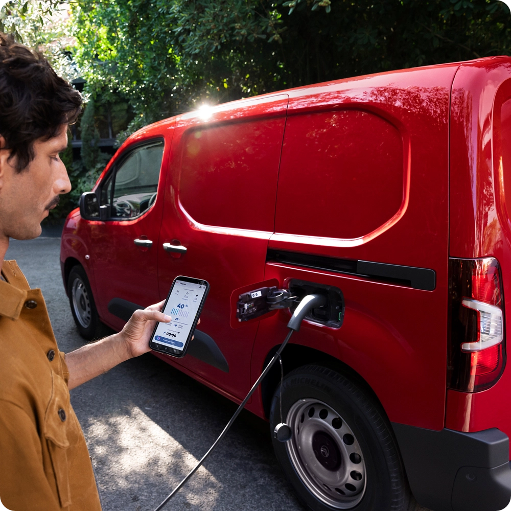 Vista lateral de três quartos de uma Citroën Berlingo Van a carregar, exibindo os serviços conectados, a utilização inteligente da energia elétrica e a praticabilidade no dia a dia.