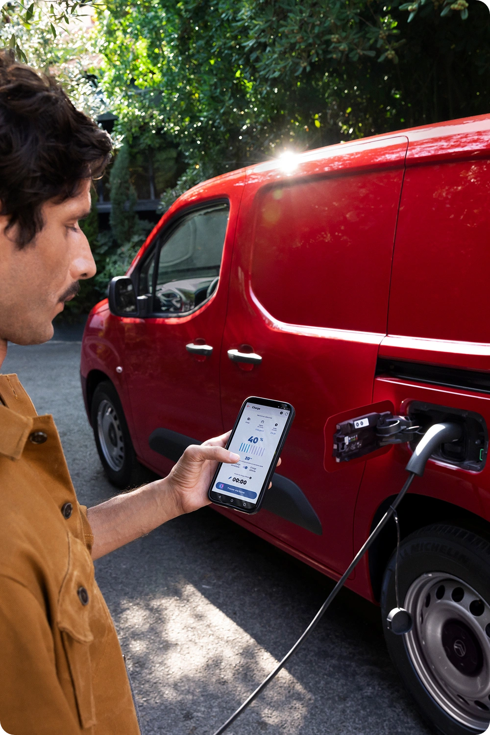 Vista lateral de três quartos de um Citroën ë-Berlingo Van a carregar, exibindo um design elétrico moderno, praticidade para o dia a dia, conectividade e uma presença confiante.