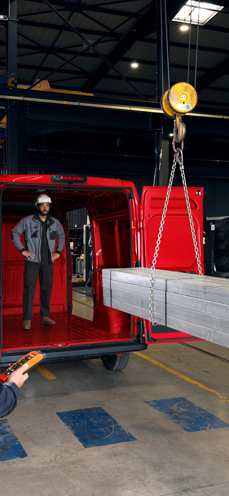 Vista traseira de um Citroën Jumper vermelho a ser carregado com vigas metálicas num ambiente industrial, destacando o grande volume de carga e a capacidade para cargas pesadas.