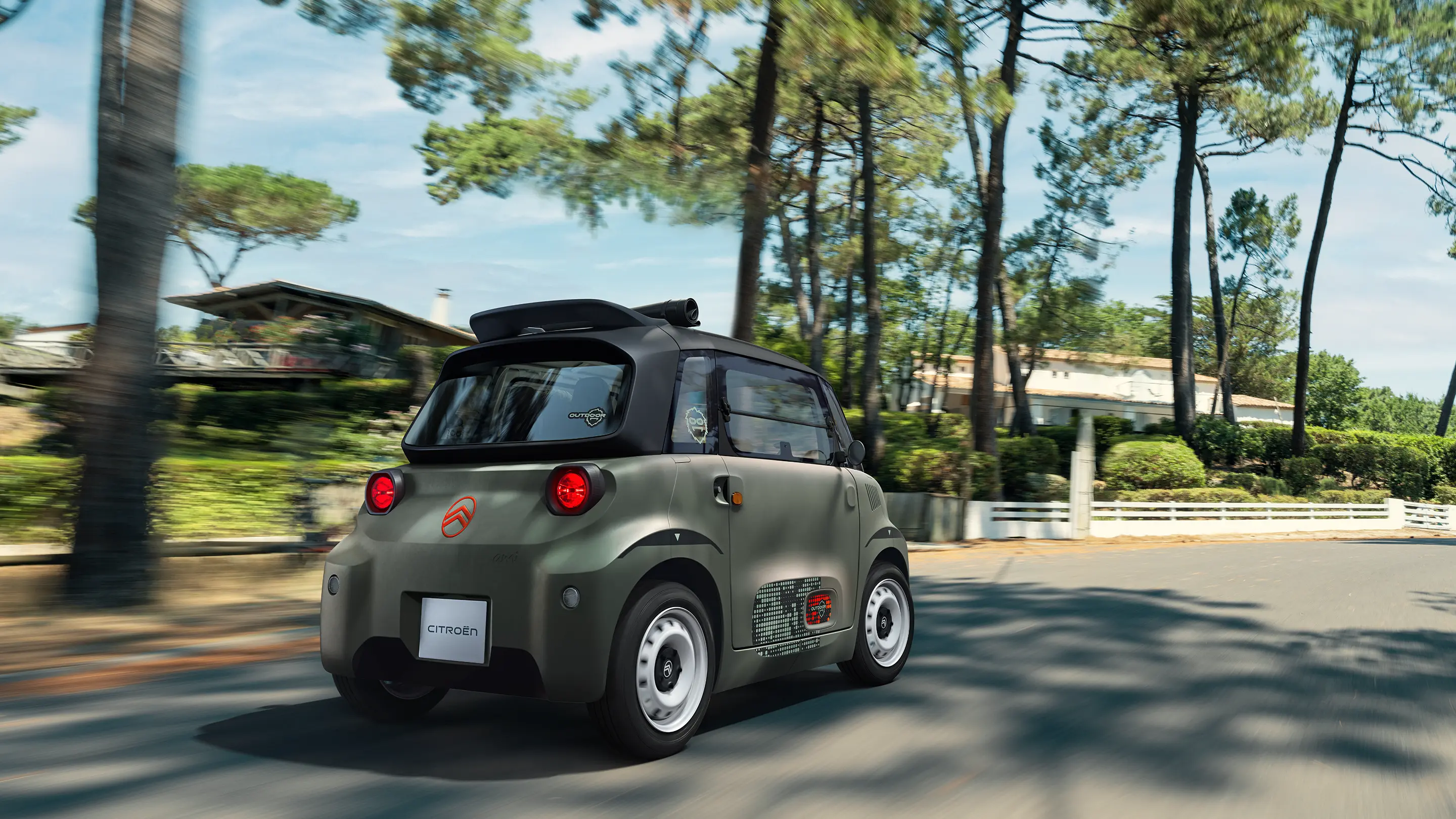 Vista traseira de três quartos do Citroën ami Outdoor com teto aberto, mostrando um automóvel urbano elétrico a circular por estradas florestais