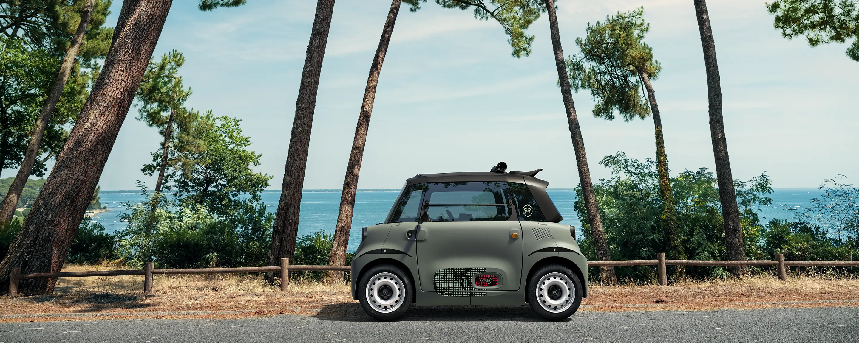 Vista frontal de três quartos do Citroën ami Outdoor com teto de lona, mostrando um automóvel urbano elétrico para a mobilidade no bairro