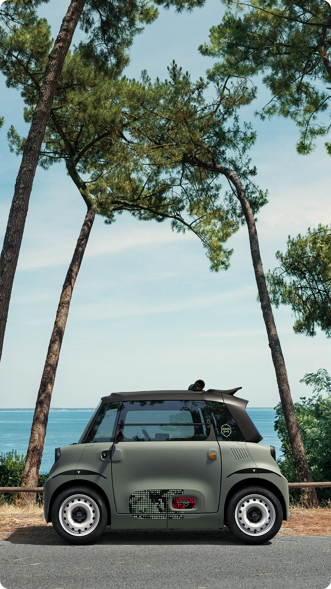 Vista lateral do Citroën ami Outdoor com teto aberto, apresentando um automóvel urbano elétrico junto à costa para mobilidade de lazer