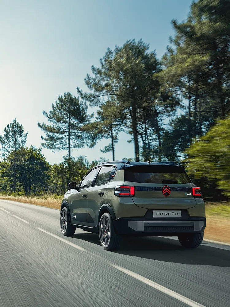Vista traseira de três quartos do Citroën C3 Outdoor com luzes traseiras LED, apresenta o SUV compacto Advanced Comfort numa estrada aberta