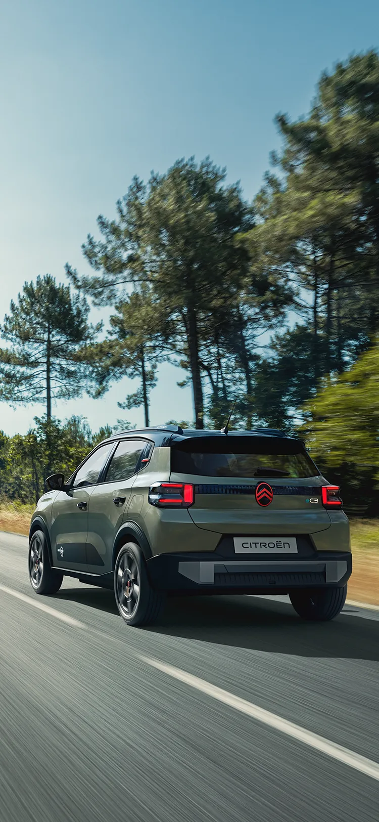 Vista traseira de três quartos do Citroën C3 Outdoor com luzes traseiras LED, apresenta o SUV Advanced Comfort numa estrada aberta