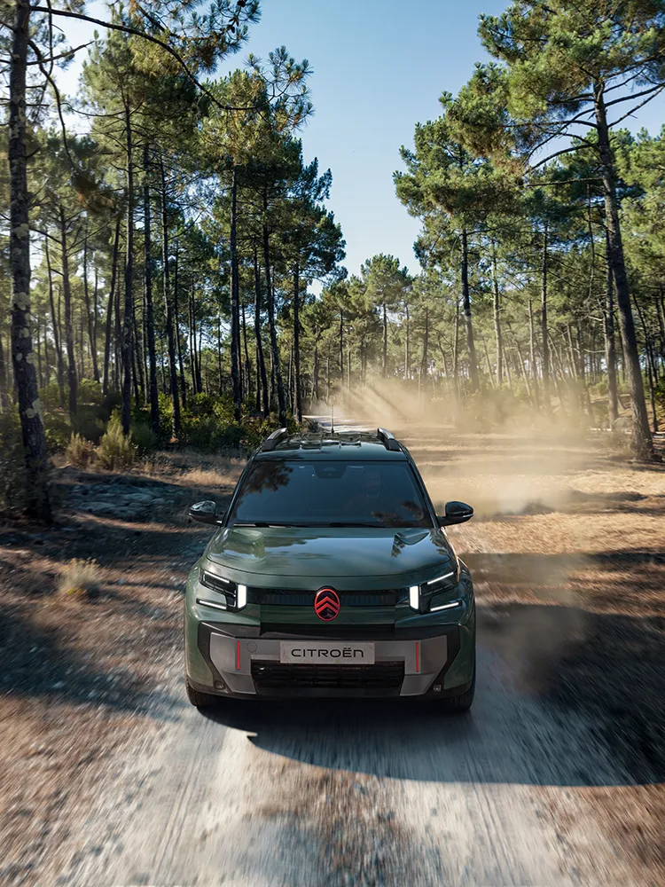 A vista aérea frontal do SUV Citroën ë-C3 Aircross mostra a assinatura LED, o Advanced Comfort e o estilo de um SUV familiar num trilho florestal