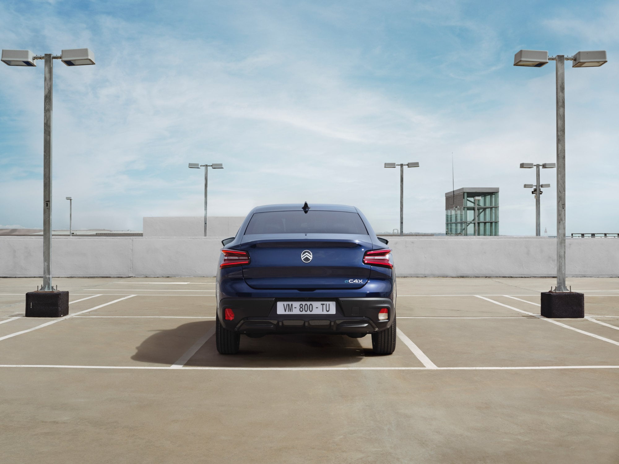 Vista traseira do Citroën C4 X num parque de estacionamento elevado, evidenciando o seu design fastback distinto para uma mobilidade elegante e acessível.