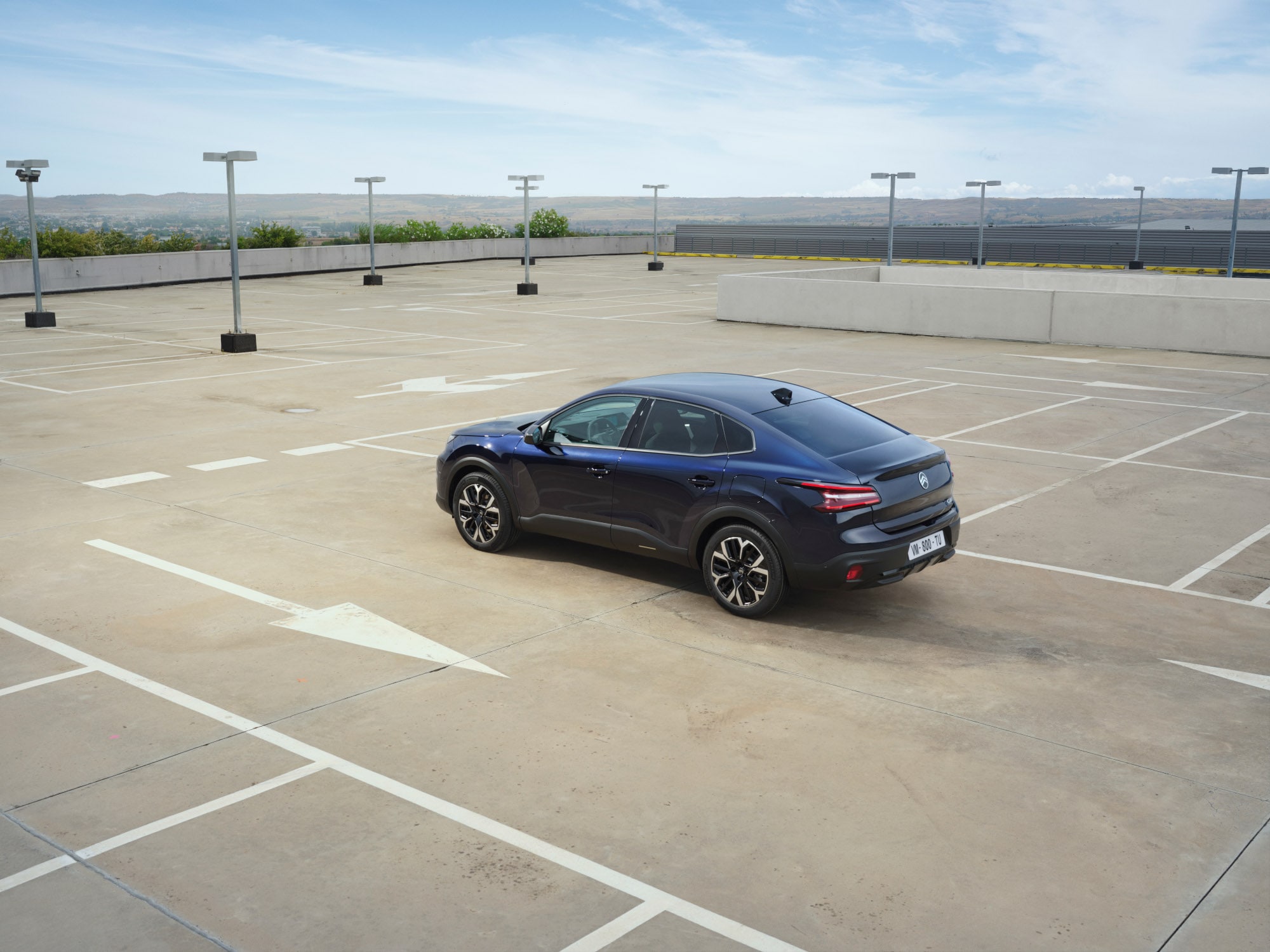 Vista traseira em três quartos do Citroën C4 X num espaço aberto de estacionamento elevado, destacando as elegantes linhas fastback para uma mobilidade acessível.