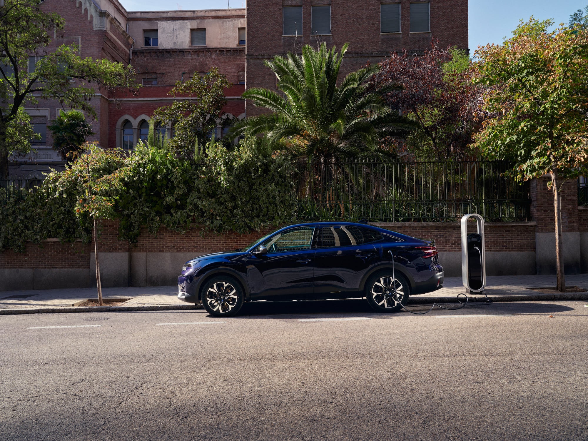 Vista lateral do Citroën C4 X fastback elétrico a carregar na rua, destacando uma mobilidade urbana prática e acessível.