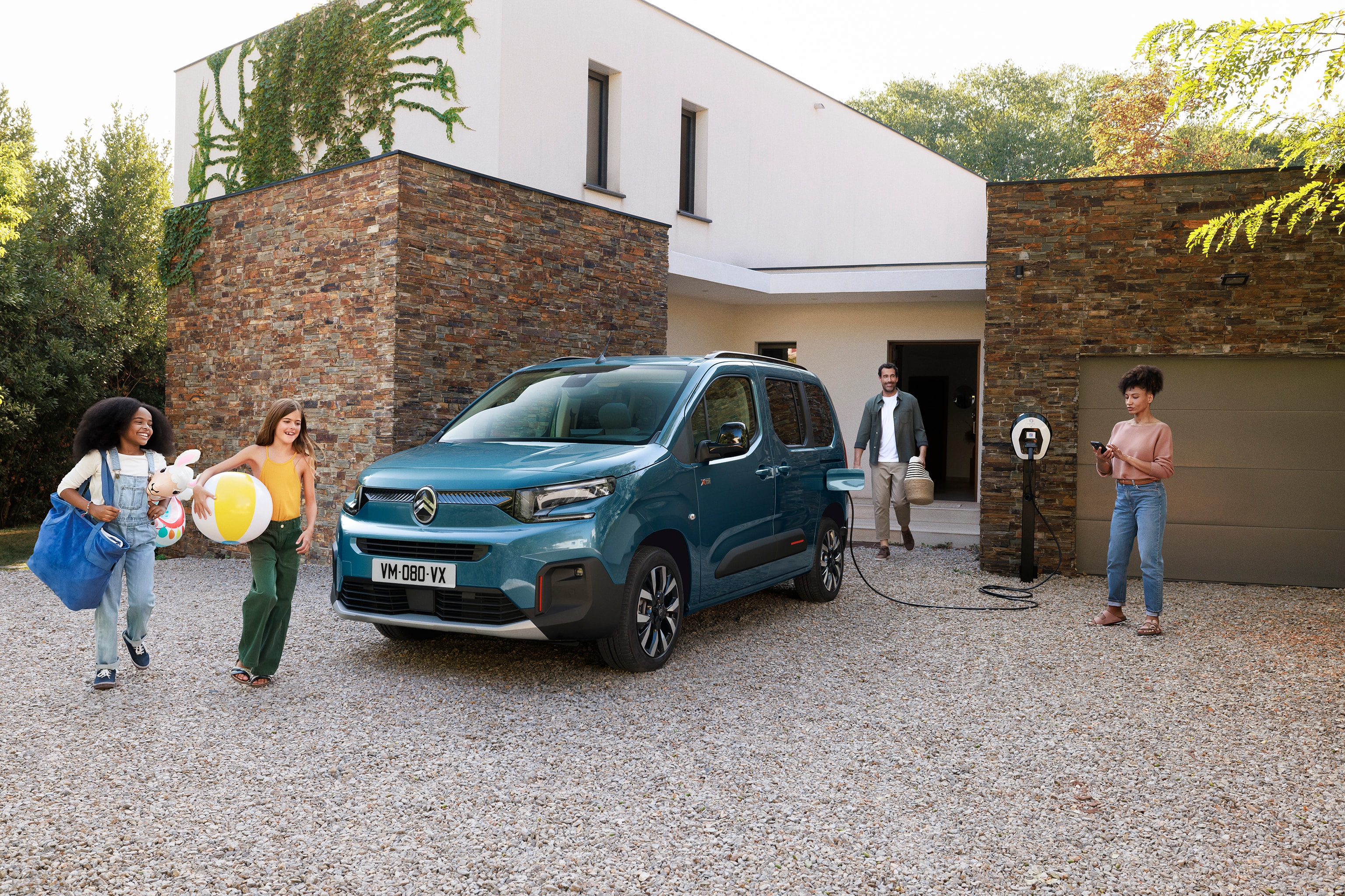 Vista dianteira em três quartos do ë‑Berlingo, evidenciando o carregamento elétrico, o conforto e a segurança para uma utilização familiar prática e tranquila.