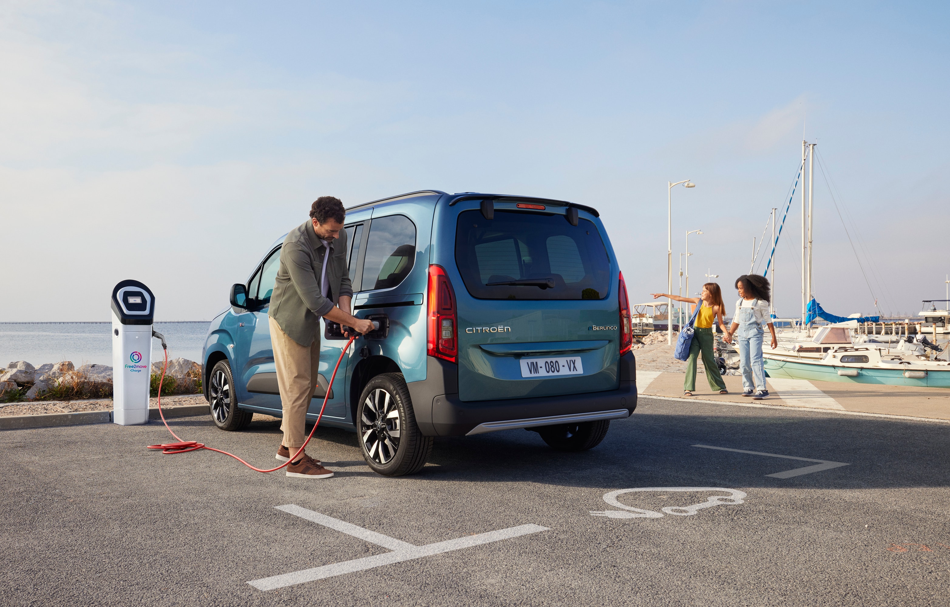 Vista traseira em três quartos do ë‑Berlingo a carregar numa estação Free2move, ilustrando uma mobilidade elétrica prática, eficiente e segura.